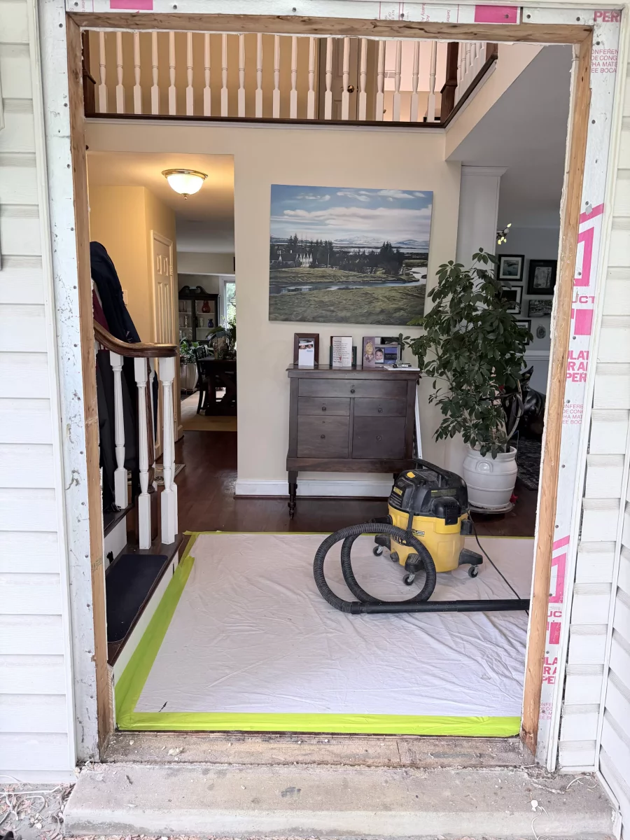 doorway with frame exposed, vacuum and drop cloth inside entry