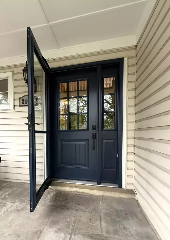 Blue entry door with glass panels and storm door on residential exterior