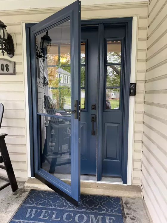 Blue storm door and entry door with glass panels on a residential porch