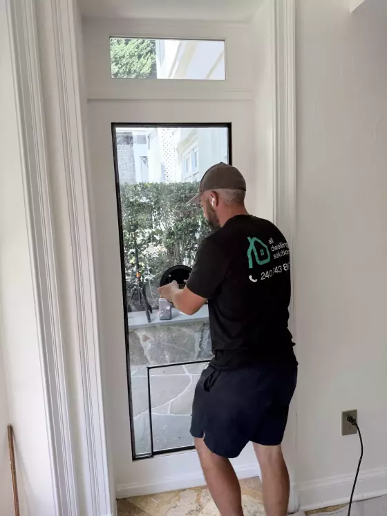 Person installing pet door in glass entry door from inside