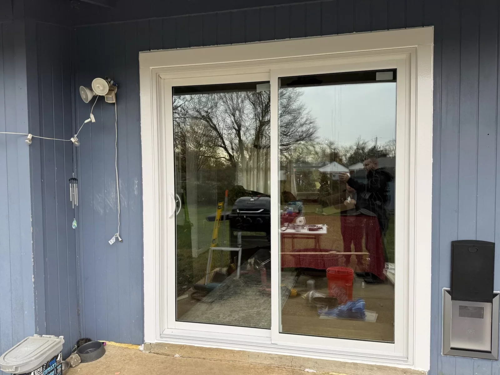 Sliding patio door installation in progress on blue exterior wall
