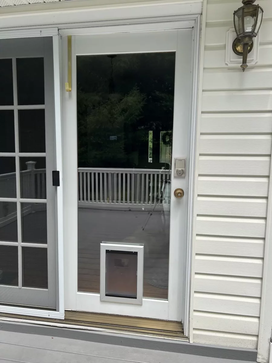 Exterior glass door with installed pet door and white siding