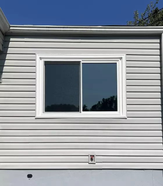 Exterior view of a sliding window installed in vinyl siding