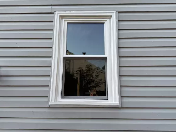single window with white trim on gray siding exterior