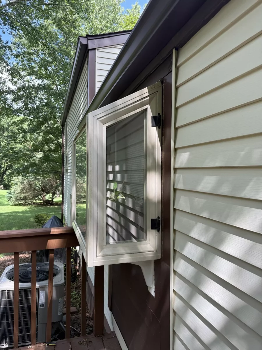 Exterior view of open casement window with siding and deck