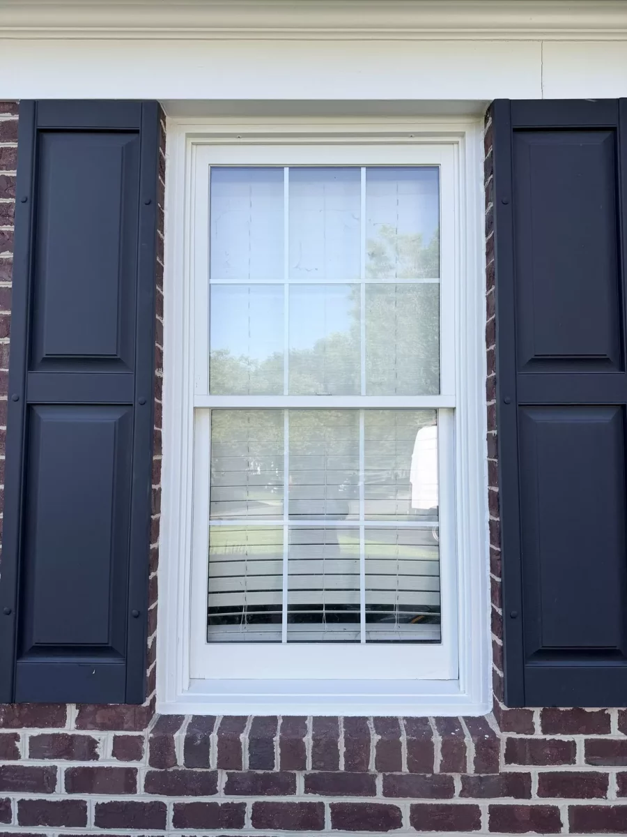 Exterior view of a residential window with brick and shutters