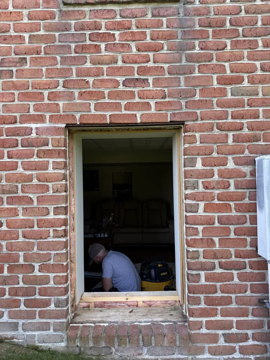 Person working on window opening in brick exterior wall