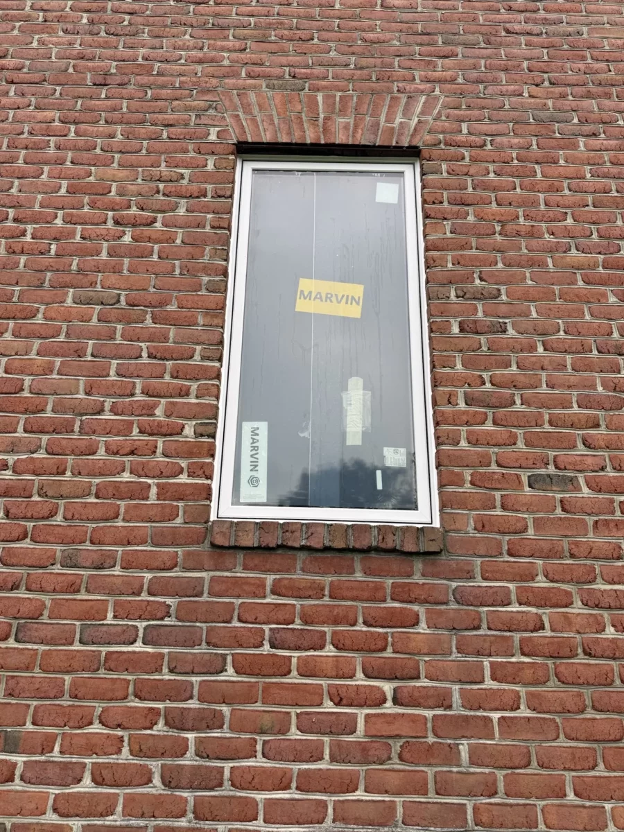 New window with protective film installed in brick exterior wall
