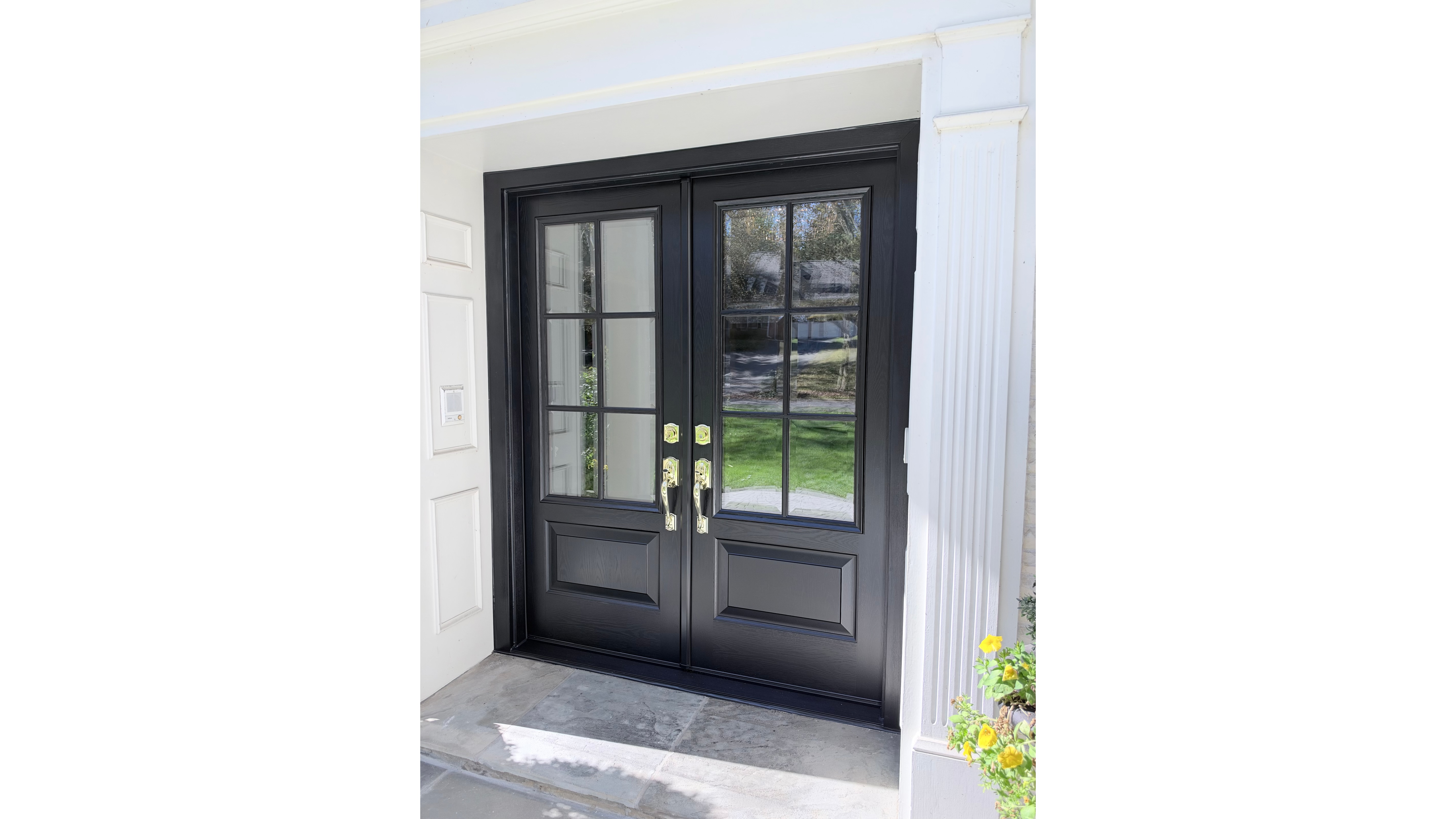 Black French front entry doors with SDL beveled grids and brass handles after a front door replacement.