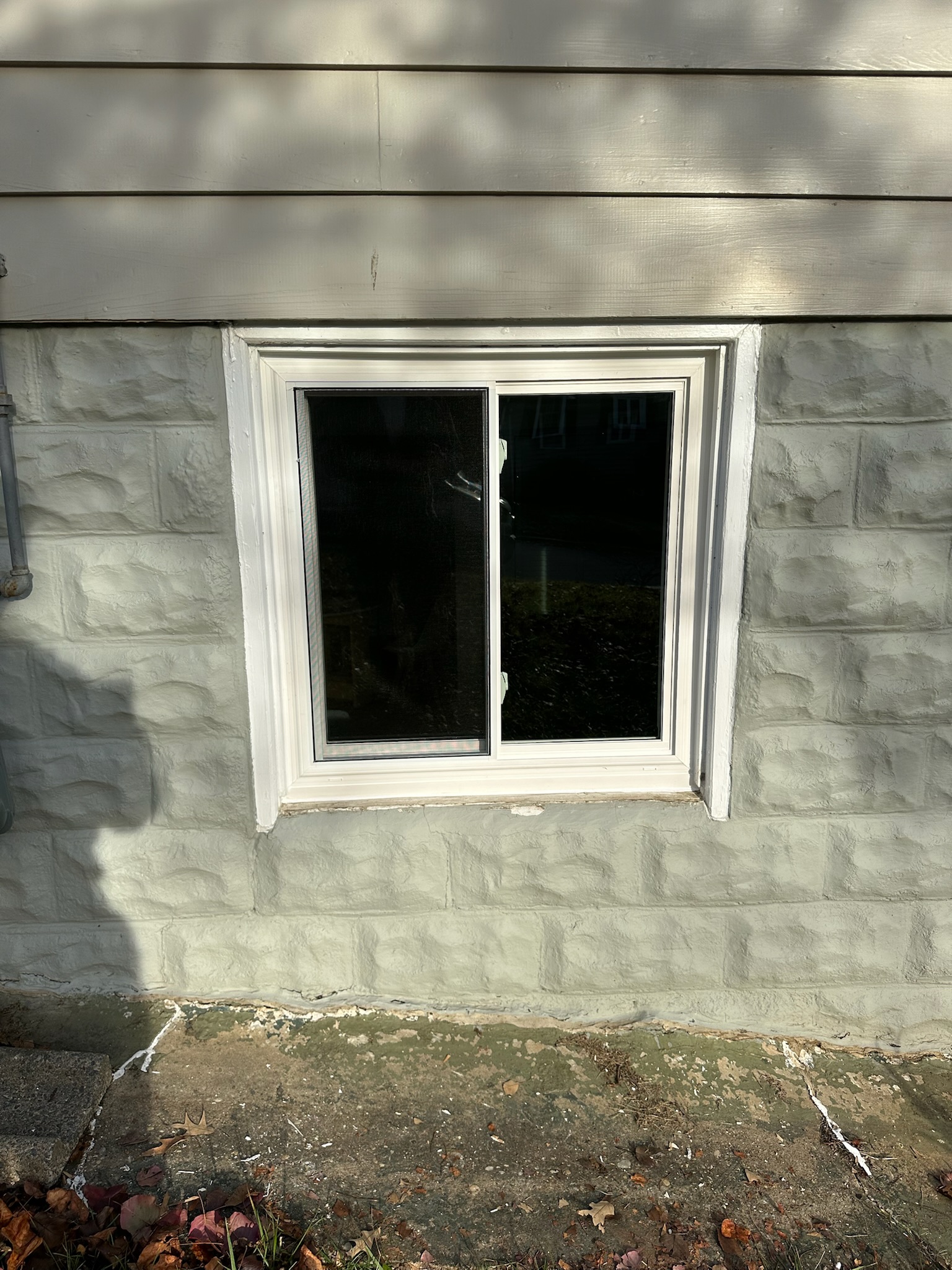 Newly installed white vinyl double-hung window exterior view after replacement.