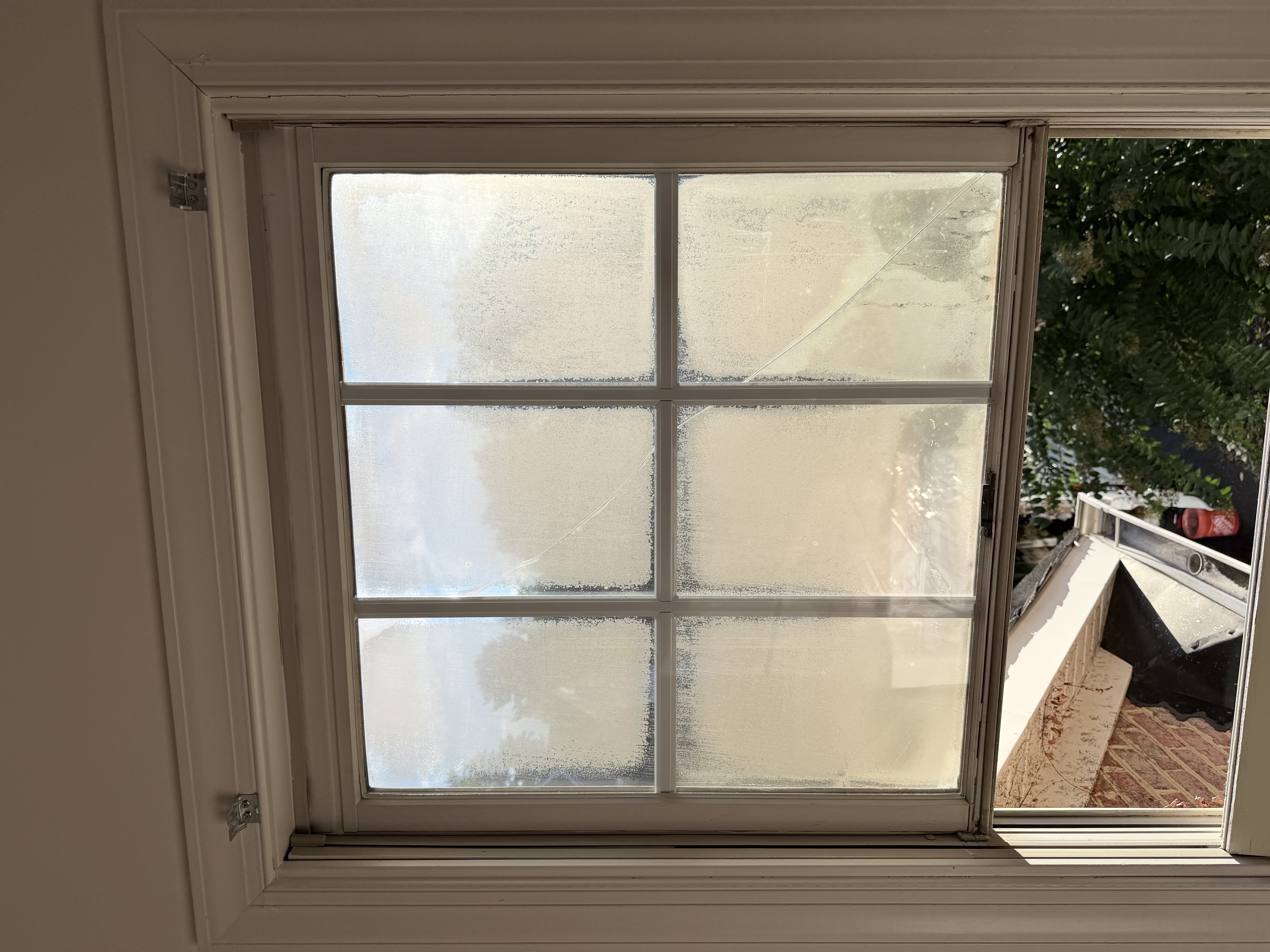 Old single-pane window with condensation and worn wooden frame before replacement.