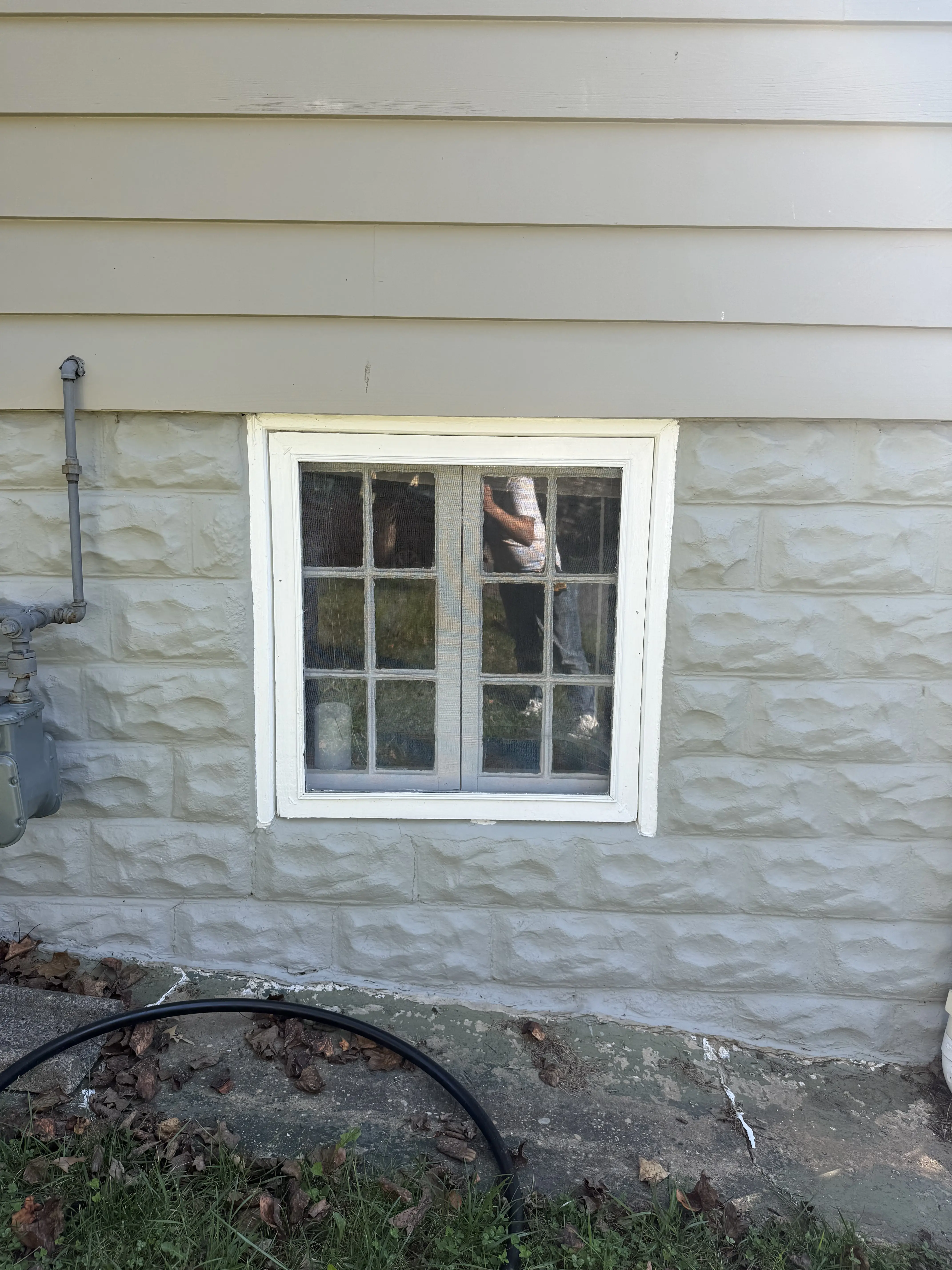 Exterior view of old vinyl window before replacement project in living room.
