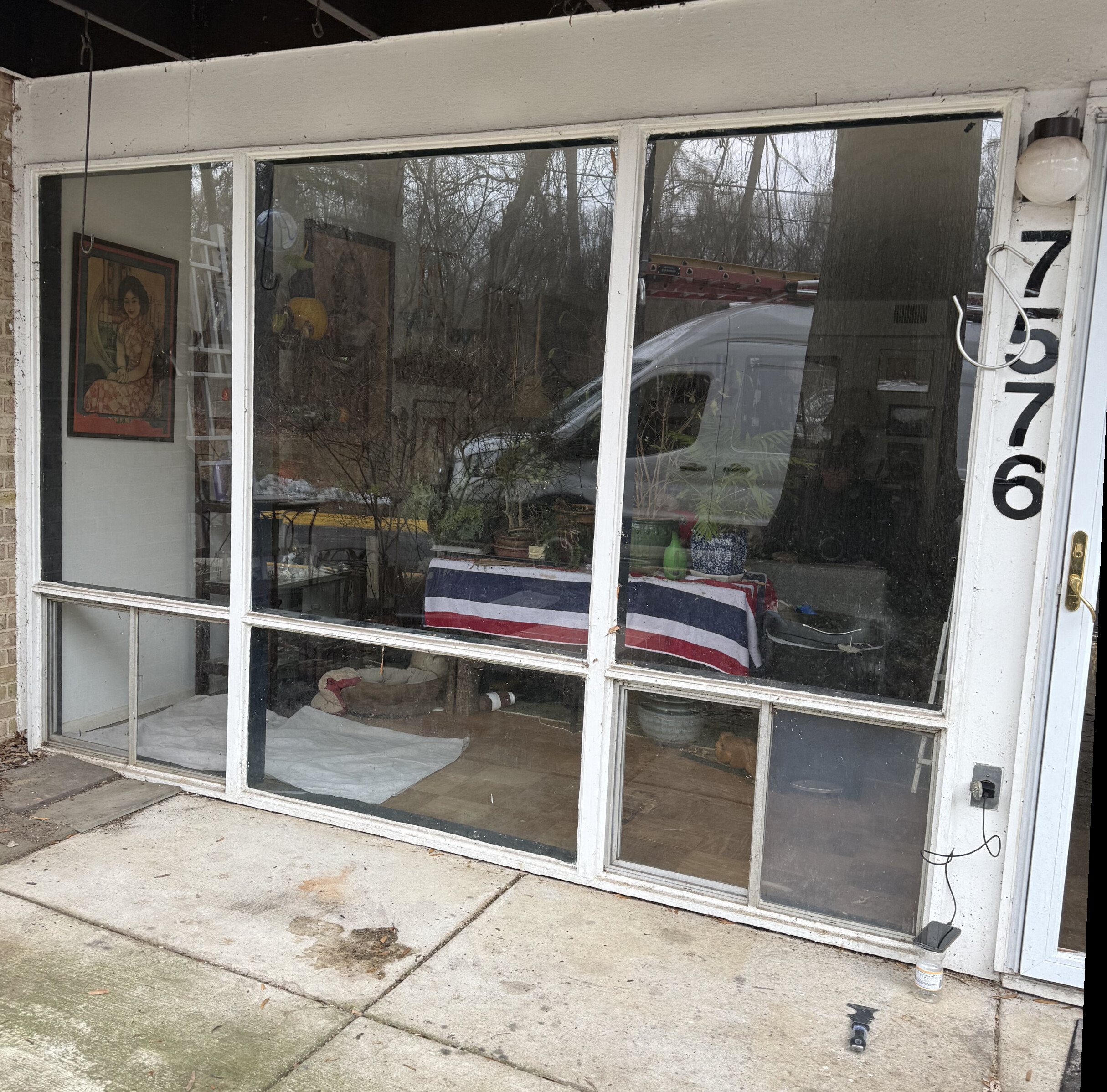 Exterior view of large residential window with white frame and concrete patio