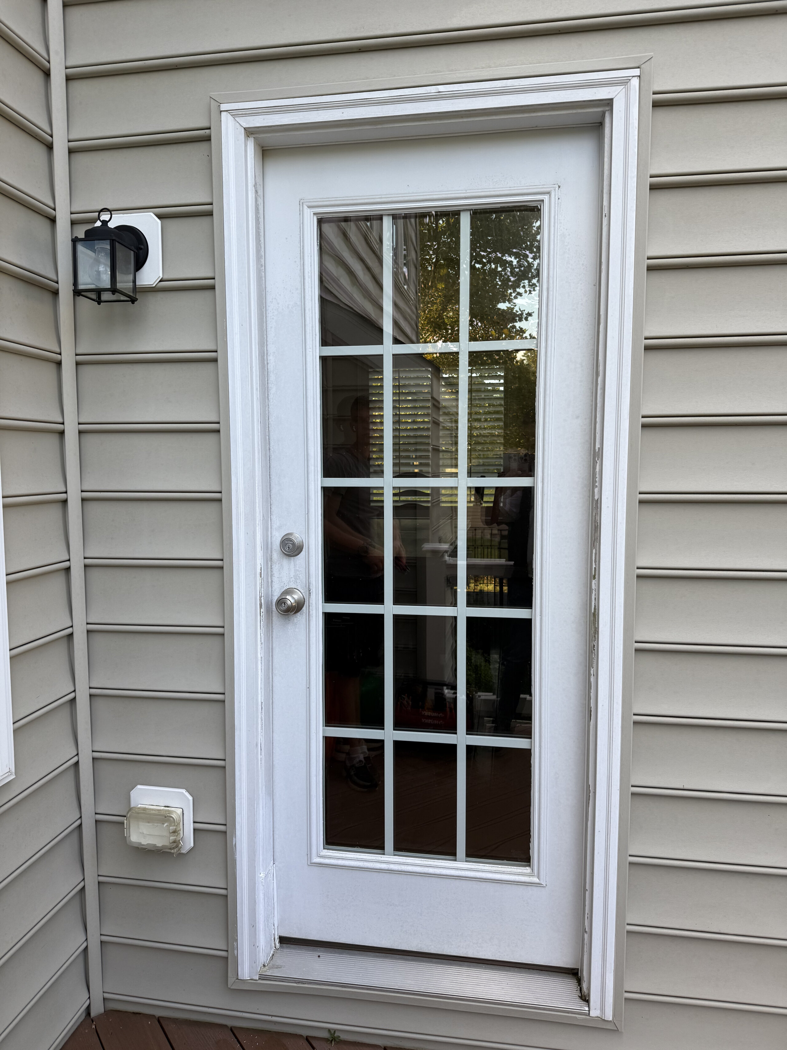 Exterior view of a white glass-panel door with surrounding siding