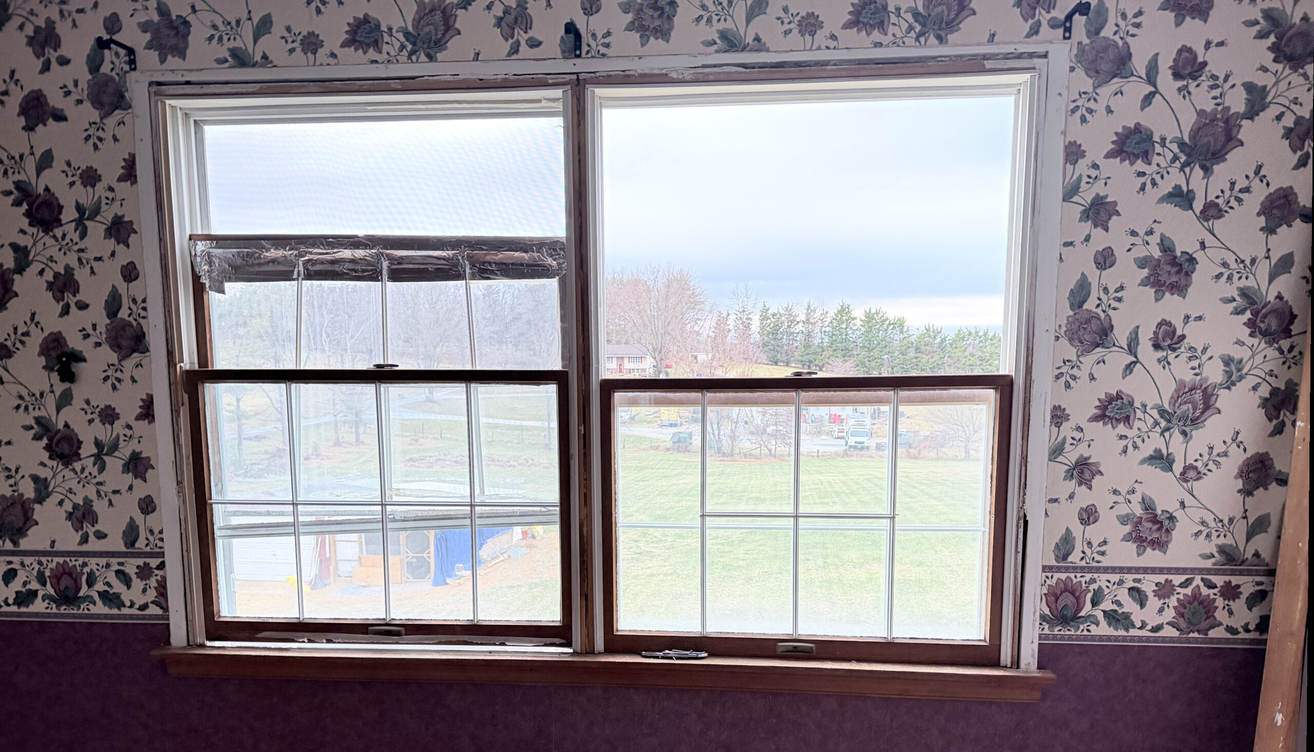 Partially installed double-hung window in a wallpapered interior room