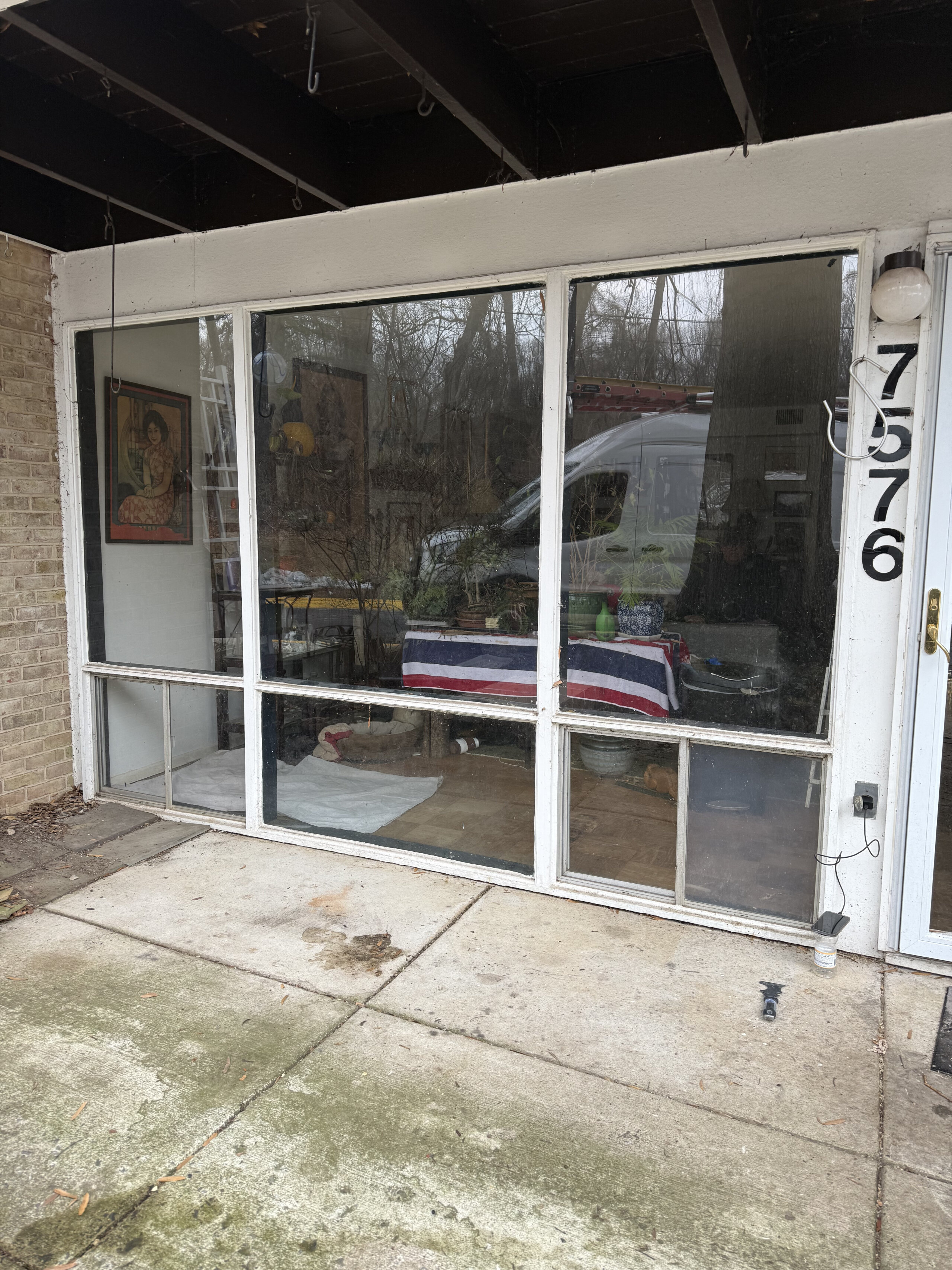 Exterior view of large residential window with white frame and concrete patio