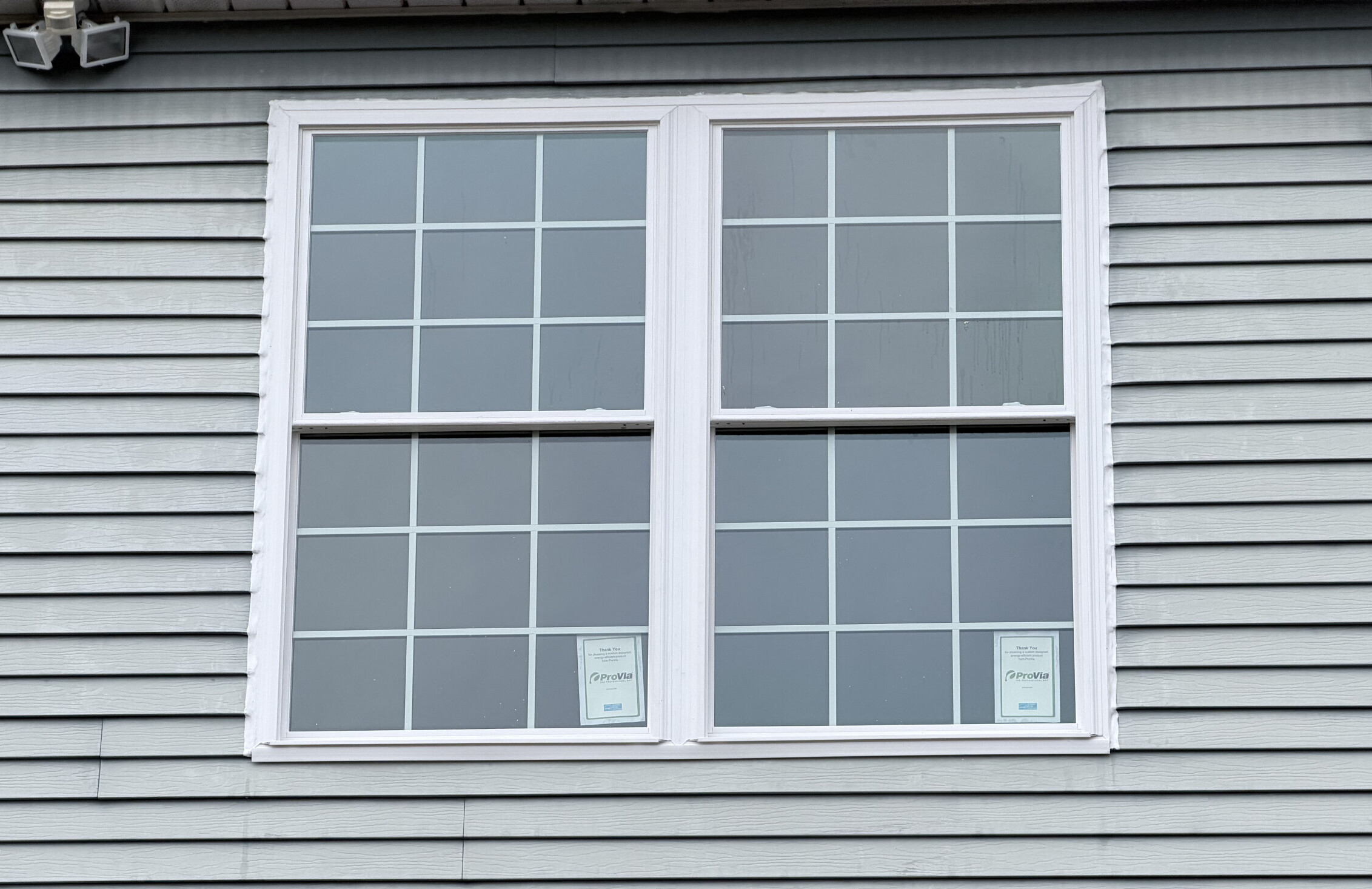 Exterior view of two newly installed double-hung windows on a house facade