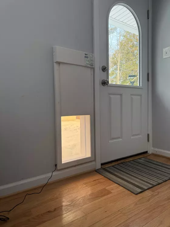 Installed pet door next to an entry door on a wood floor