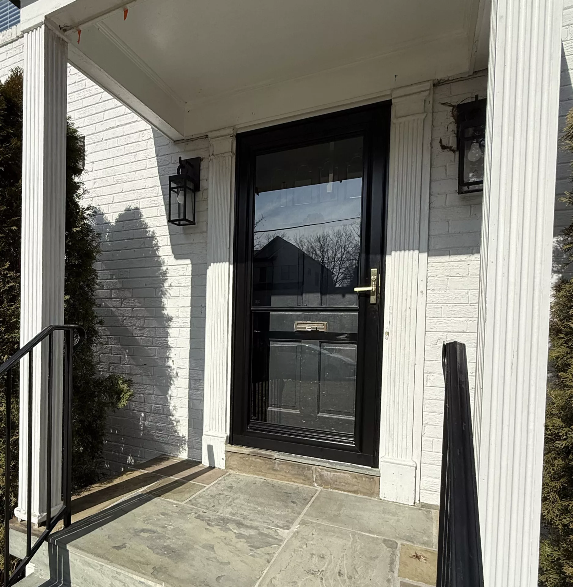 Exterior view of a house entry with a glass door and stone steps