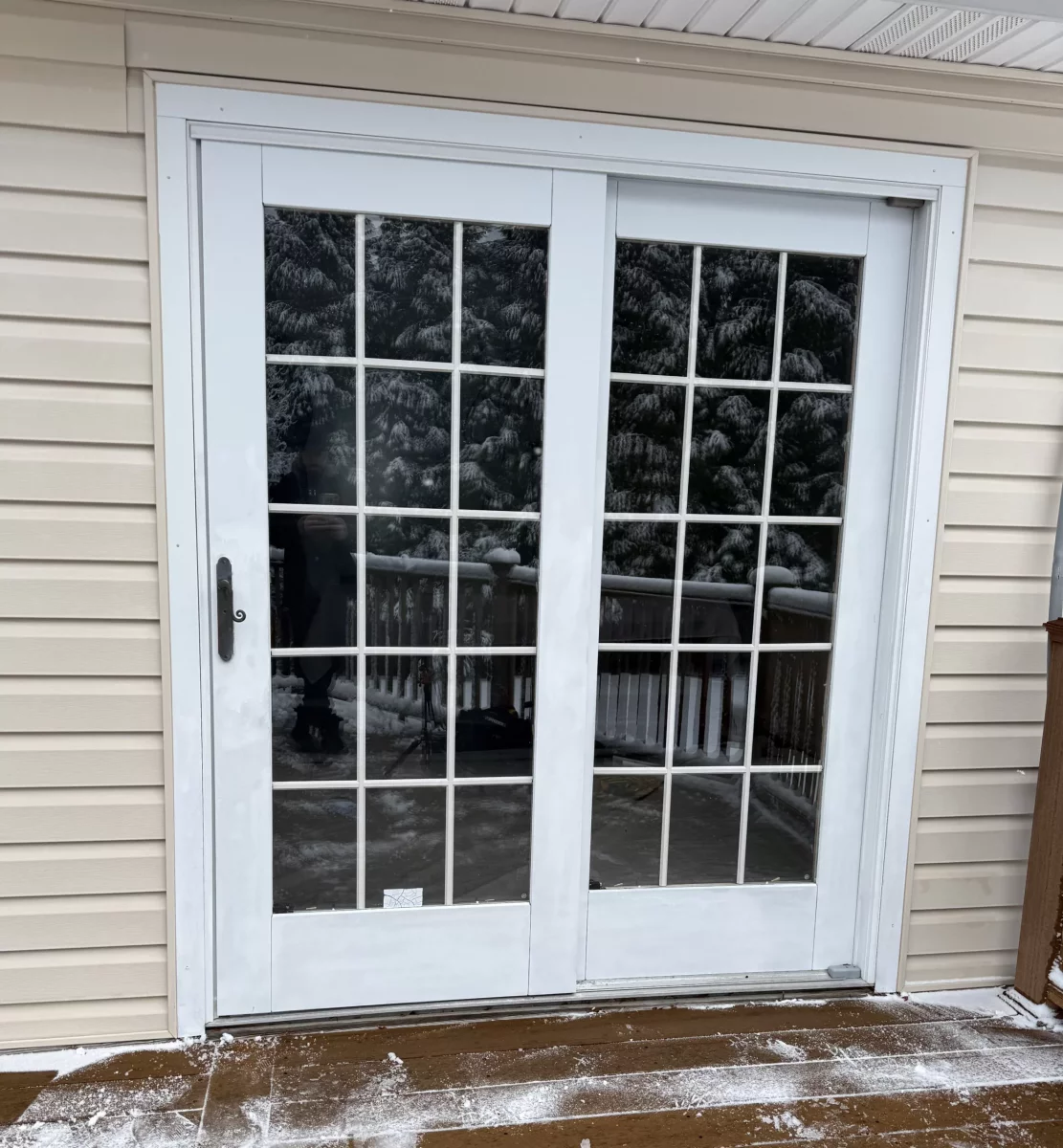 White patio doors with glass panes on a snowy deck