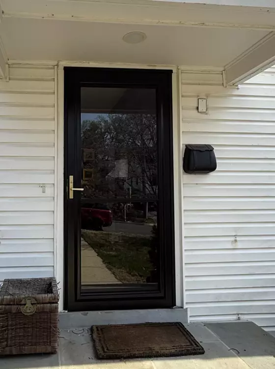 Front exterior of a house with a black entry door and white siding