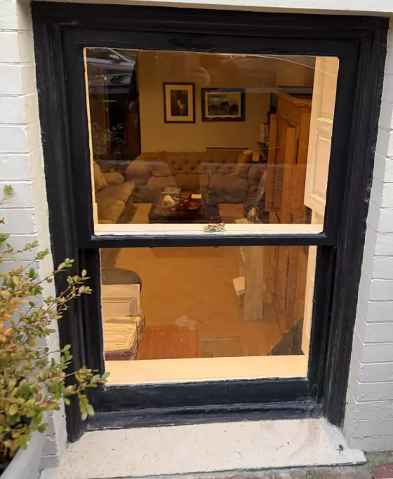 Exterior view of a window with black trim and visible interior room
