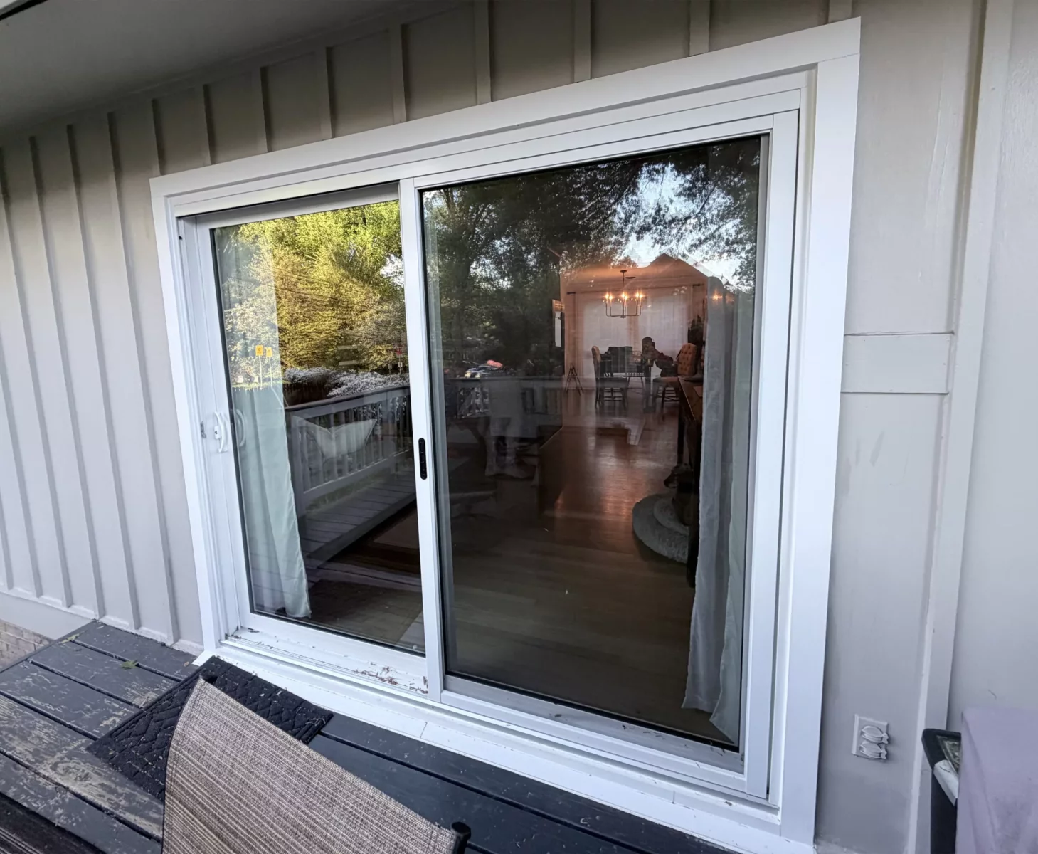 White sliding patio door installed on exterior deck with siding