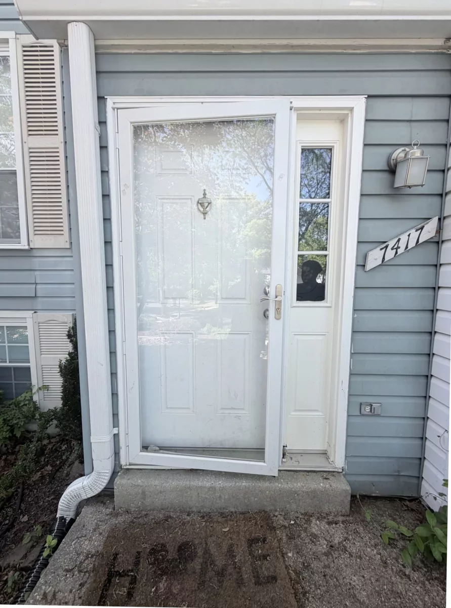 Exterior view of a front door with a storm door and siding