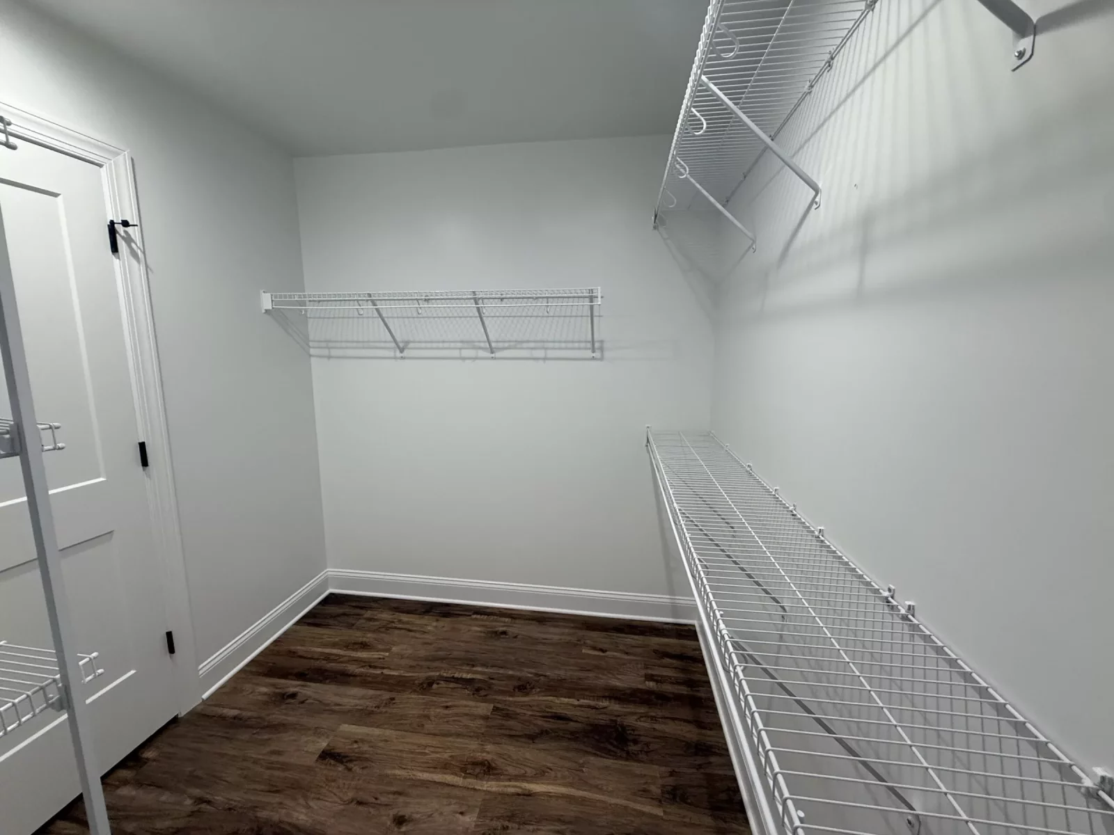 Spacious walk-in closet with white wire shelving and wood-look flooring