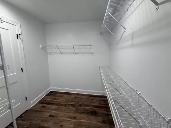 Spacious walk-in closet with white wire shelving and wood-look flooring