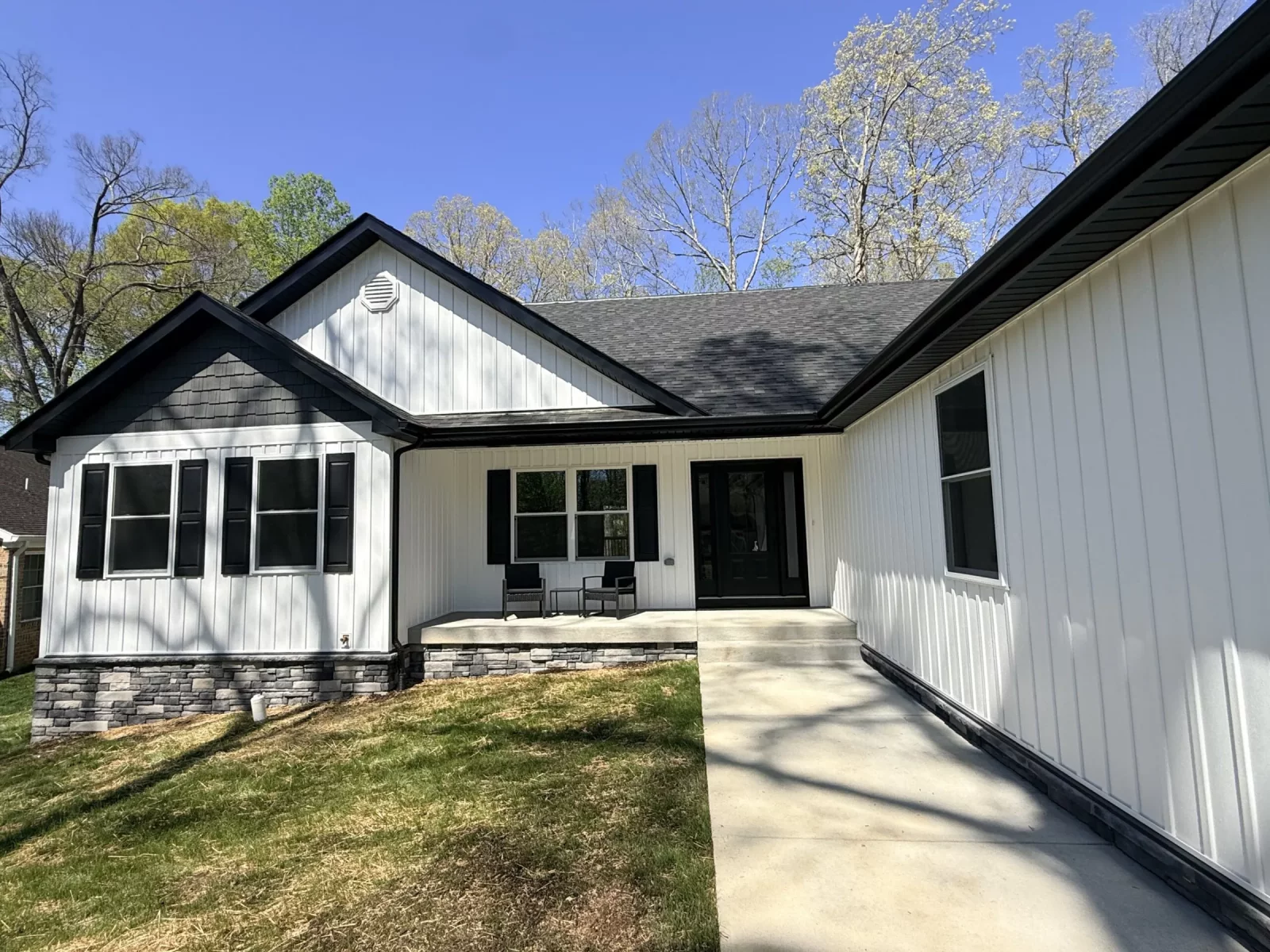 Modern farmhouse exterior with white board-and-batten siding, black-framed windows, and a covered front entry
