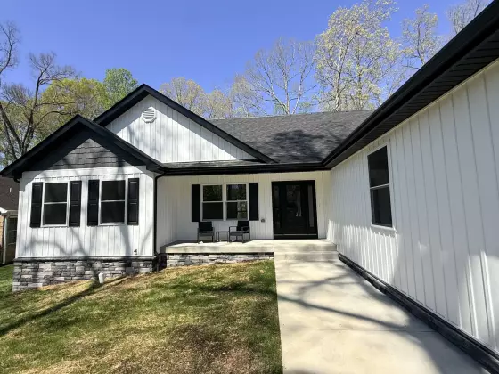 Modern farmhouse exterior with white board-and-batten siding, black-framed windows, and a covered front entry