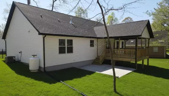 Rear of a newly constructed home with a covered deck, white siding, and a level grass yard