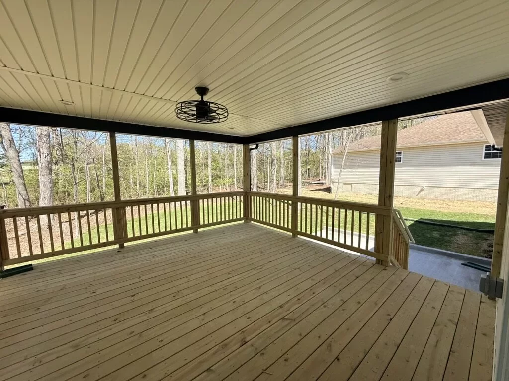 Covered back porch with a wood-plank ceiling and ceiling fan overlooking the backyard