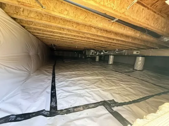 Encapsulated crawl space with vapor barrier and insulation beneath the custom-built home
