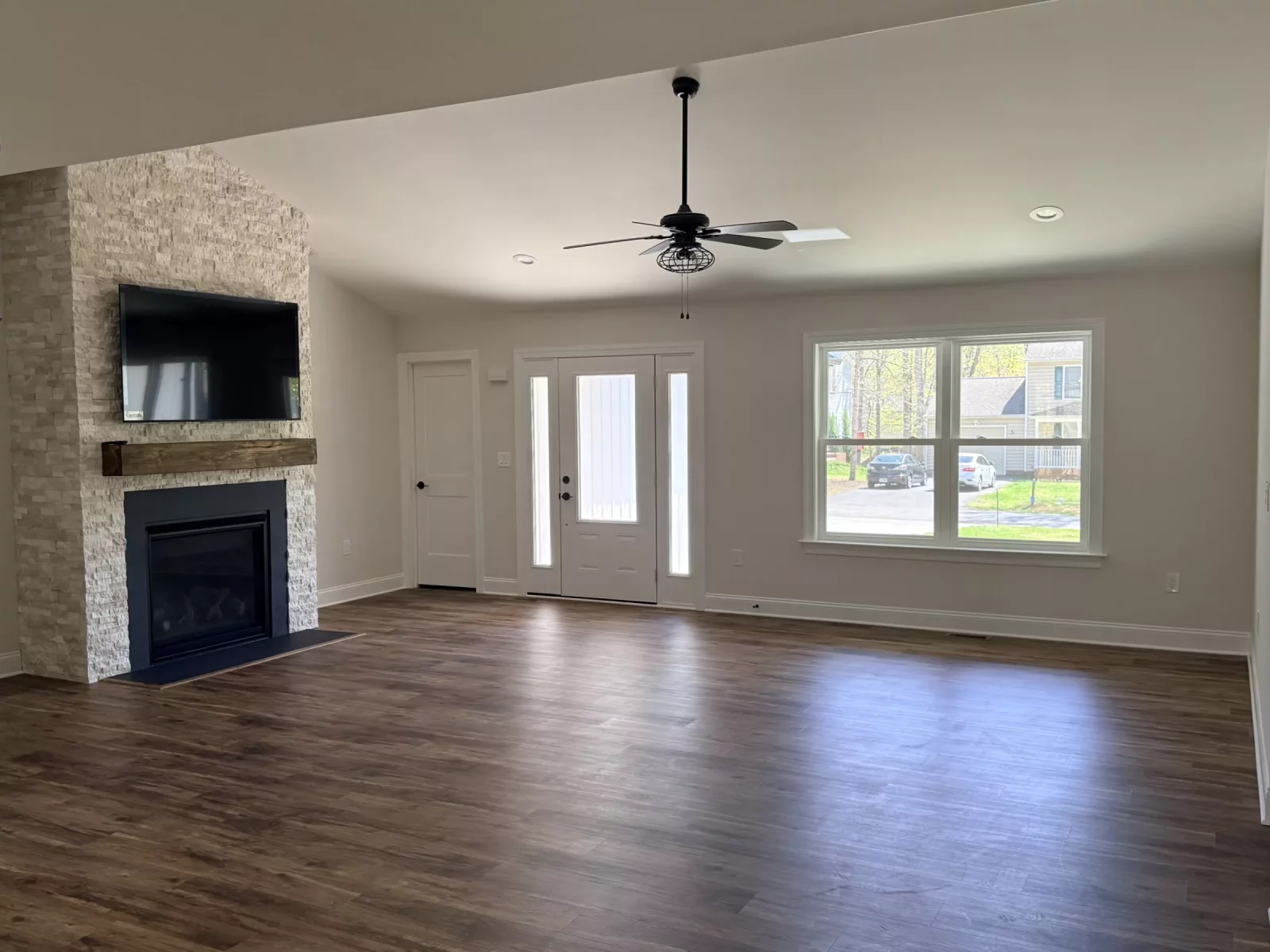 Open-concept great room with French doors, large windows, and wood-look flooring in a new custom home