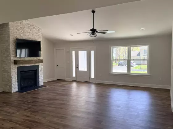 Open-concept great room with French doors, large windows, and wood-look flooring in a new custom home