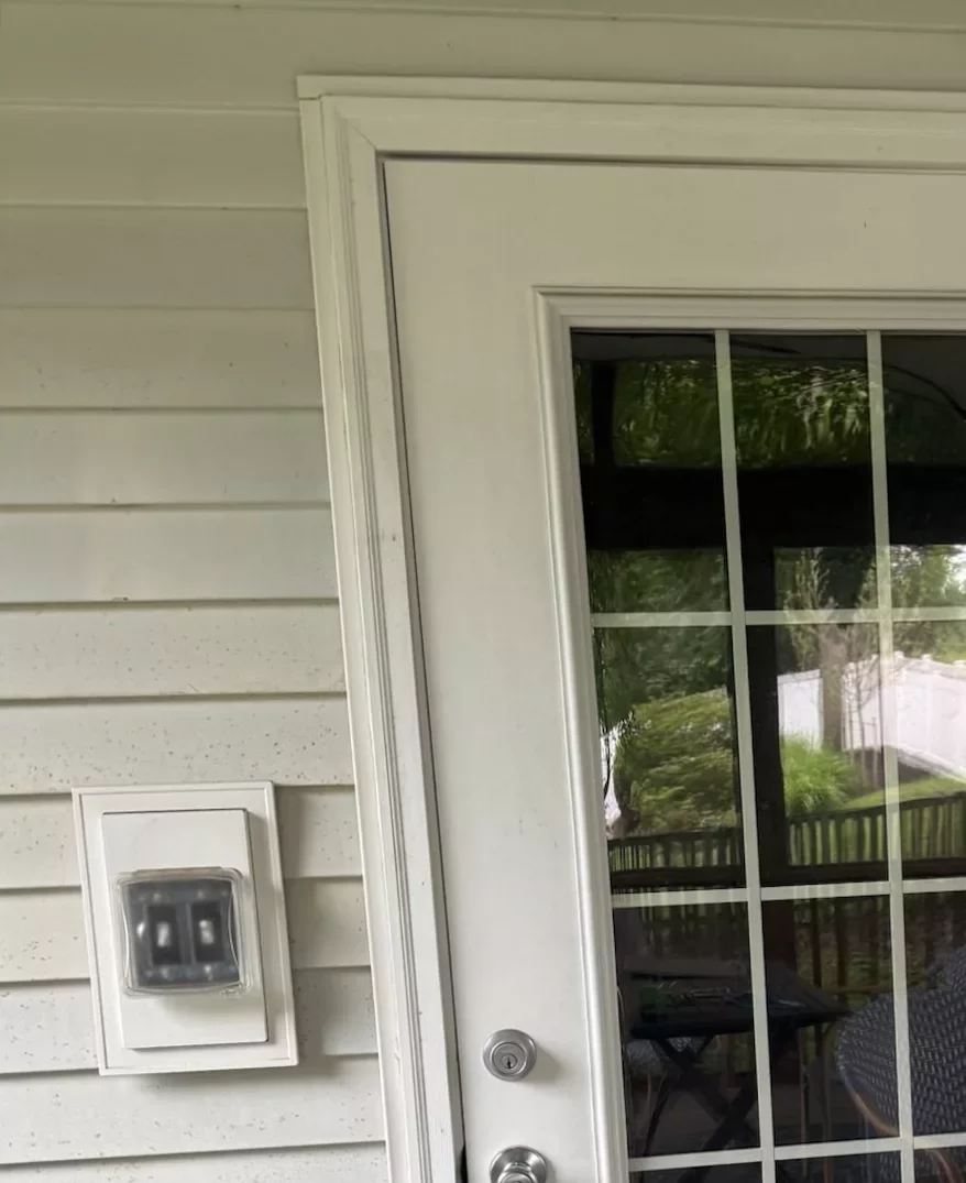 White exterior door with glass panels and green doormat on porch