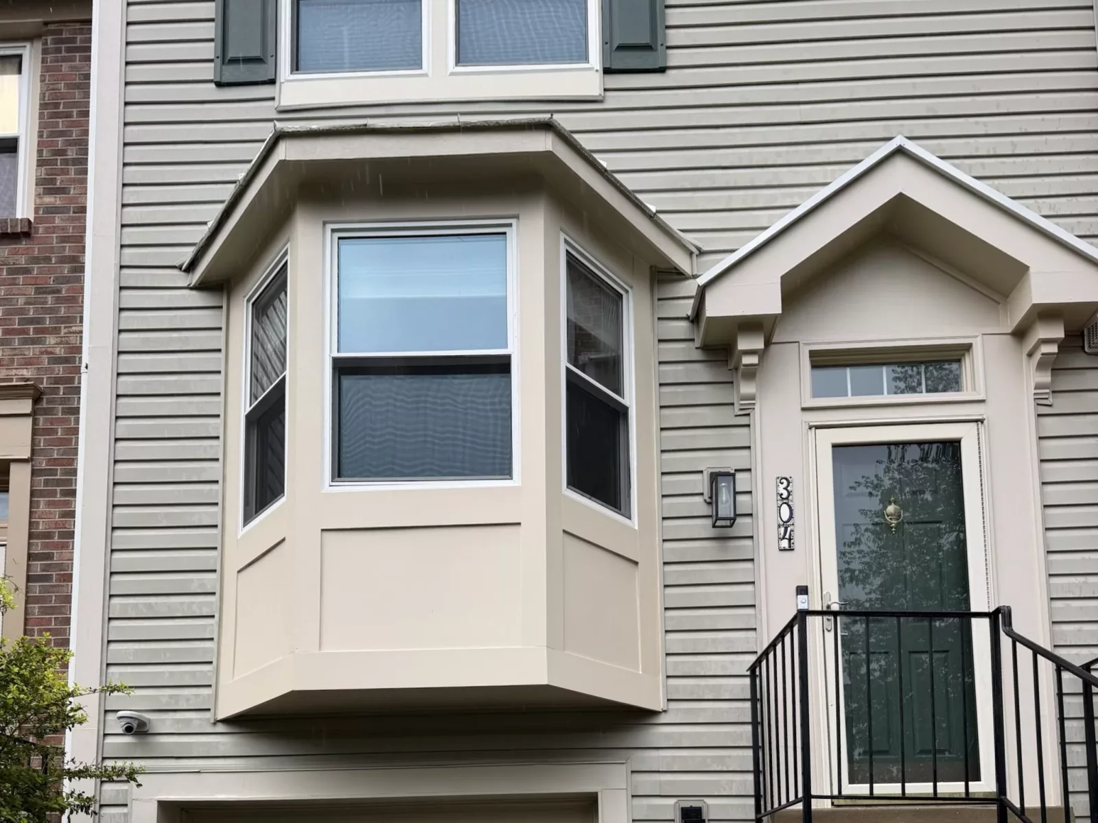 Residential building exterior with bay window, siding, entry door, and garage door
