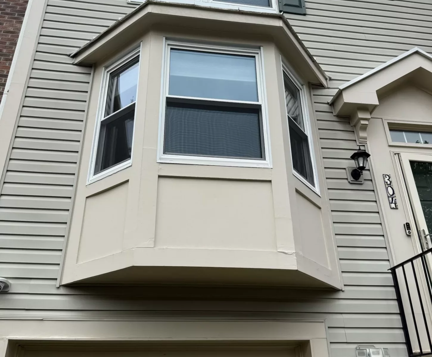 Exterior view of a house with bay window and siding above a garage door