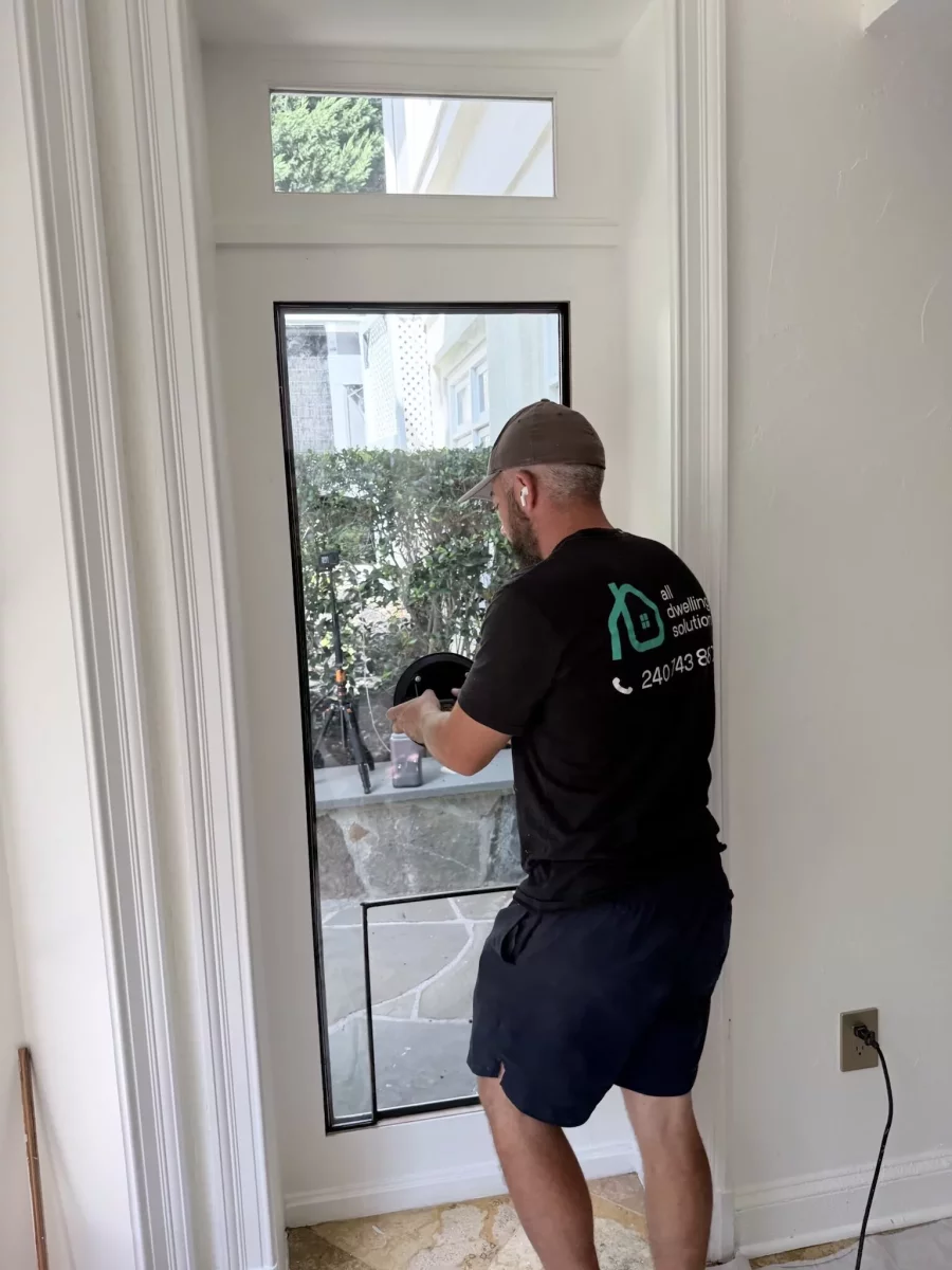 Person installing pet door in glass entry door from inside