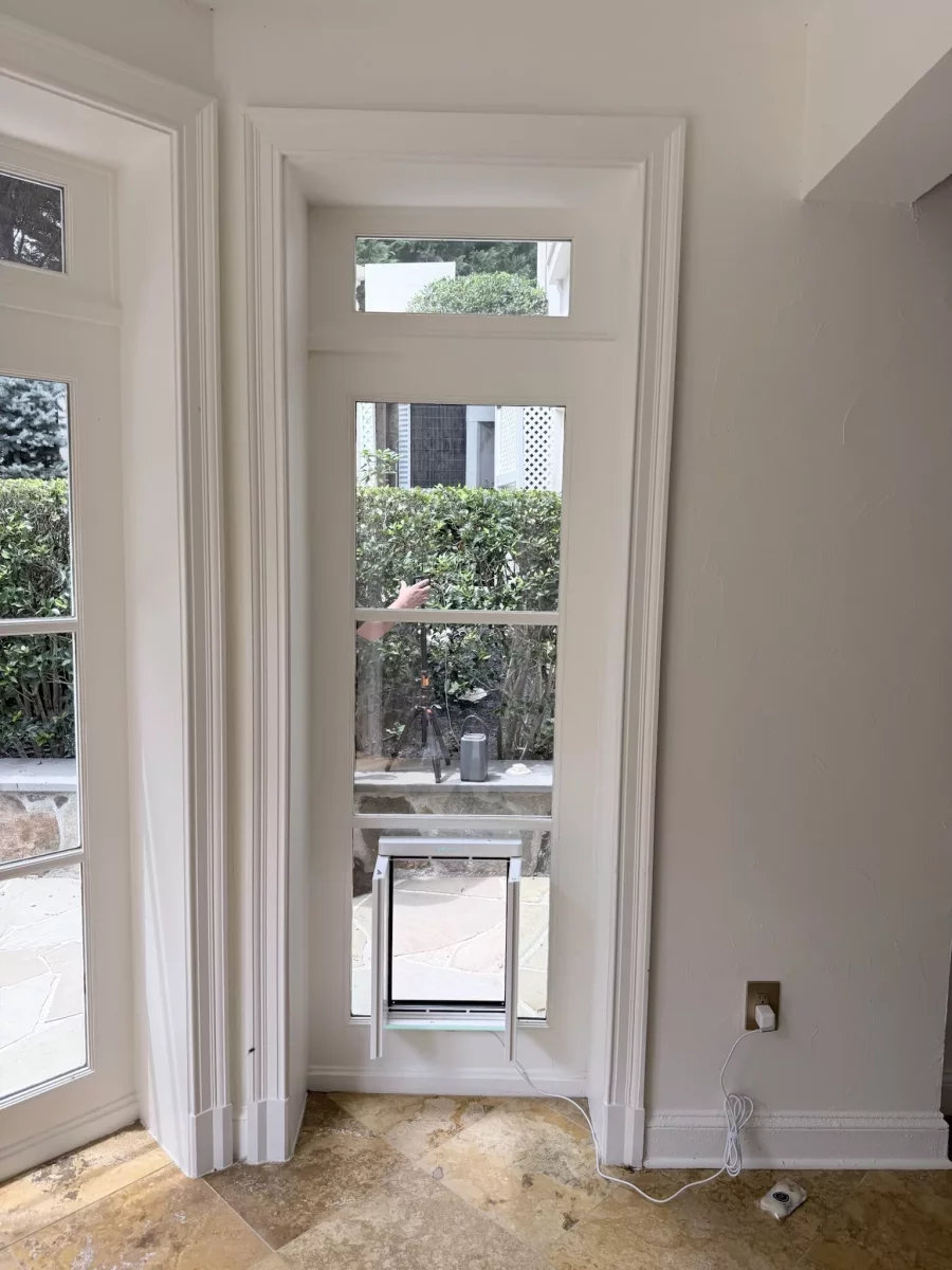 Pet door installed in a window with white trim inside a home