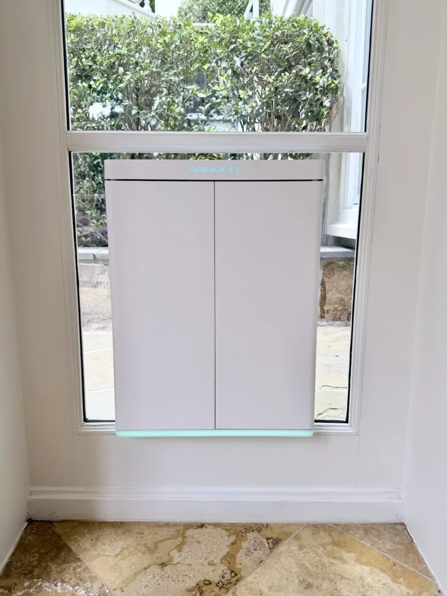 Installed pet door in glass window with tiled floor