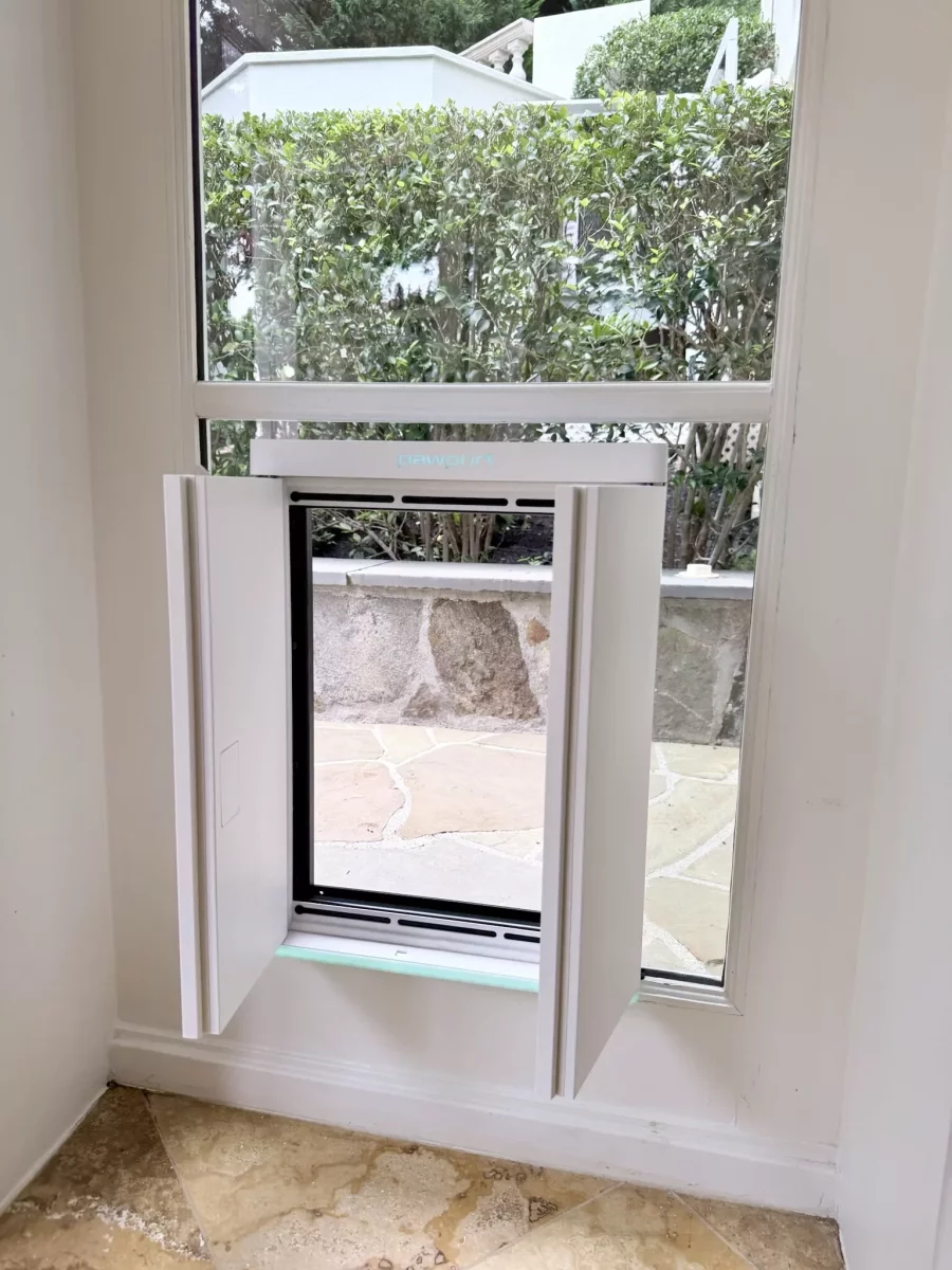 Installed pet door in window with open panels inside residential room