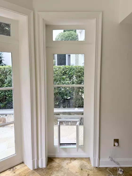 Interior window with installed pet door and tile floor