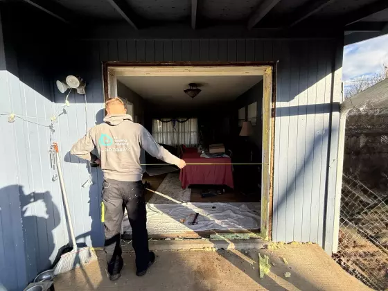 Worker measuring exterior door frame during replacement project