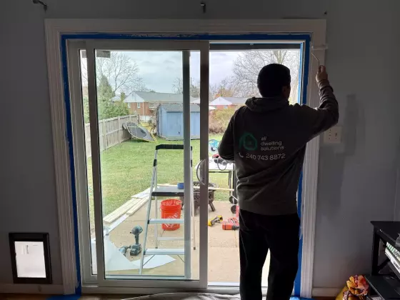 Person painting trim around sliding patio door during installation
