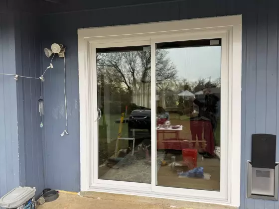 Sliding patio door installation in progress on blue exterior wall