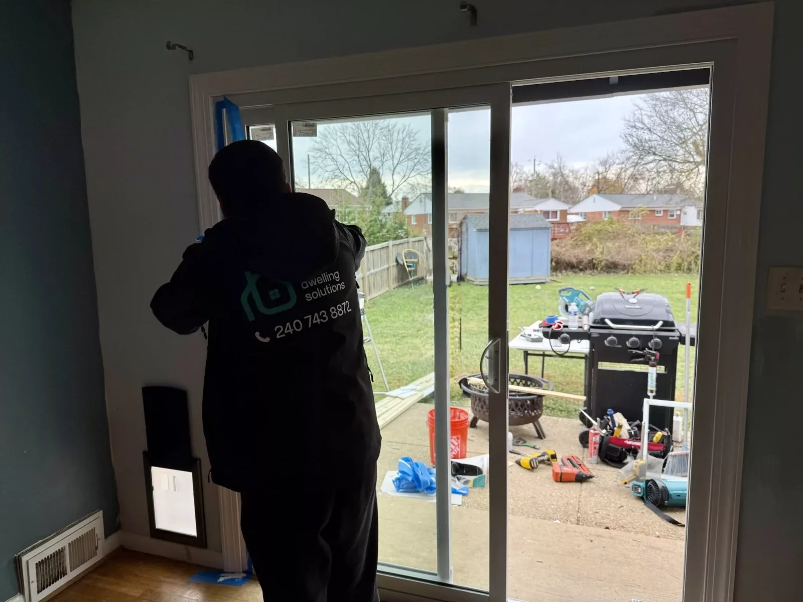 Person installing sliding patio door with tools visible inside and outside