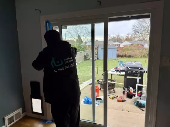 Person installing sliding patio door with tools visible inside and outside